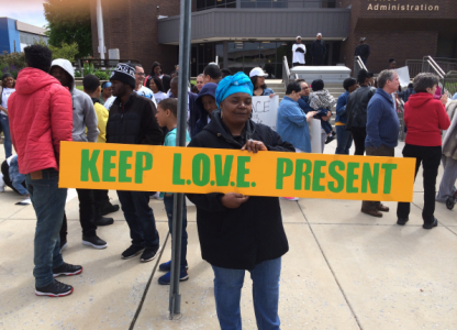 Sonya Murrell holding up a keep love present sign at a community rally in camden, nj